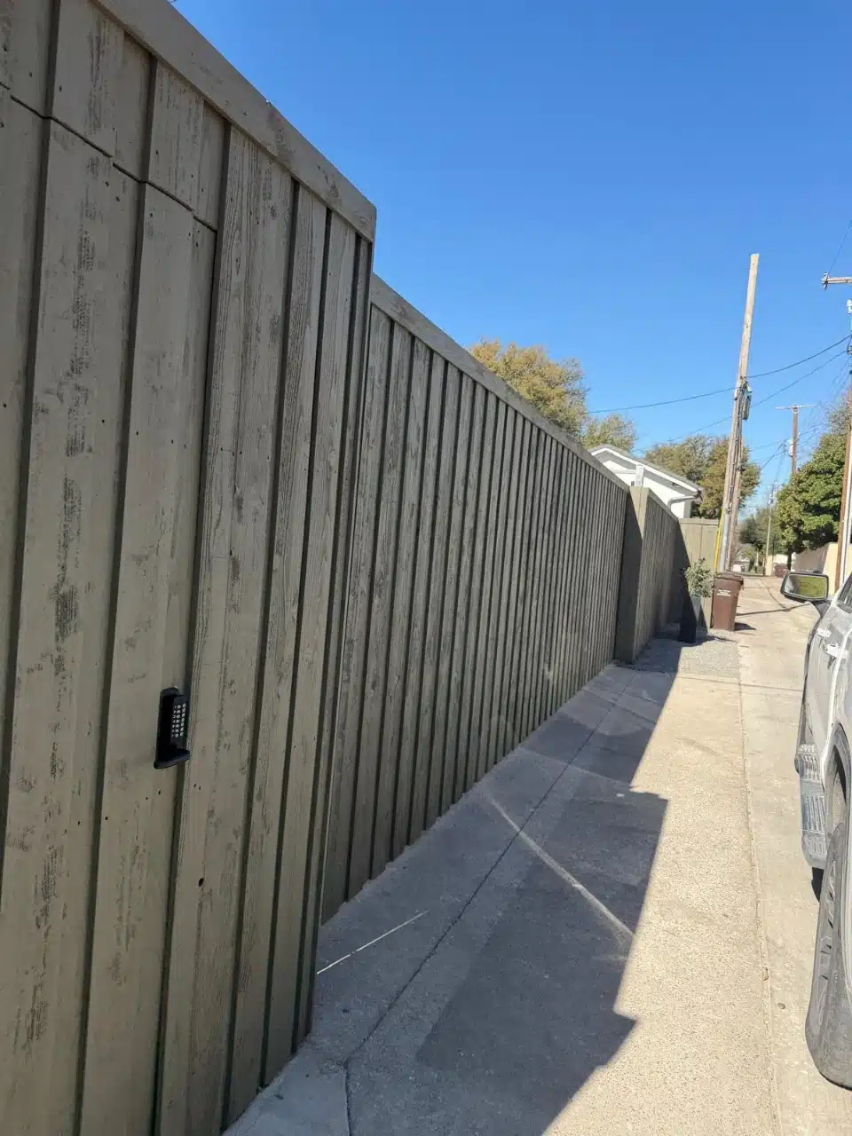 Cedar-clad sliding driveway gate closed across an alley entrance in Highland Park