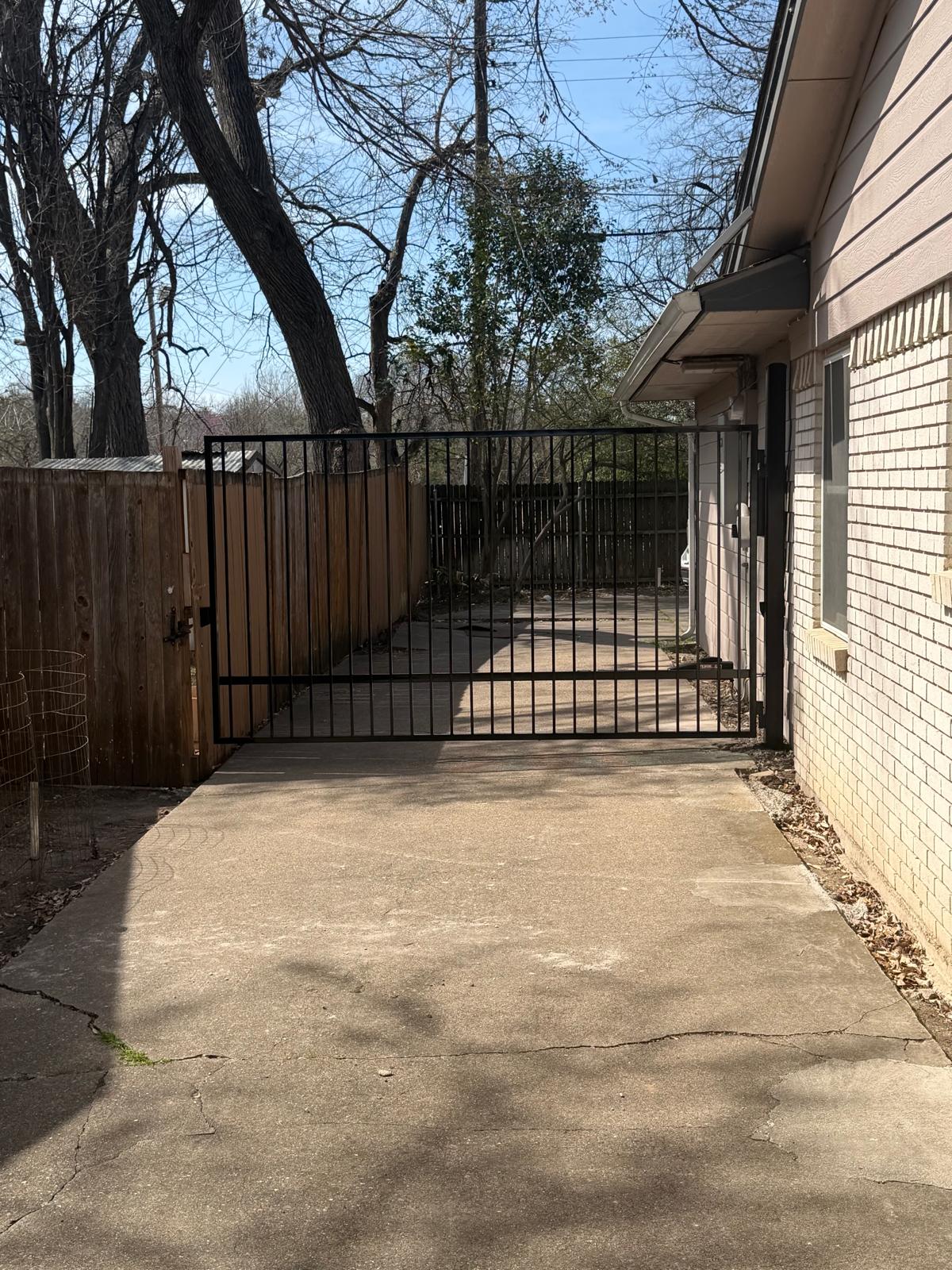 Double iron swing gate closing a side driveway in Dallas 75208