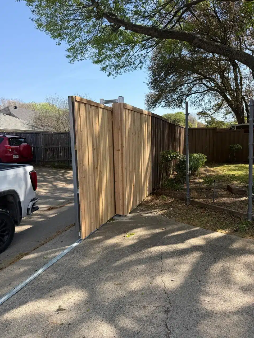 Cedar slide gate standing open at the driveway approach