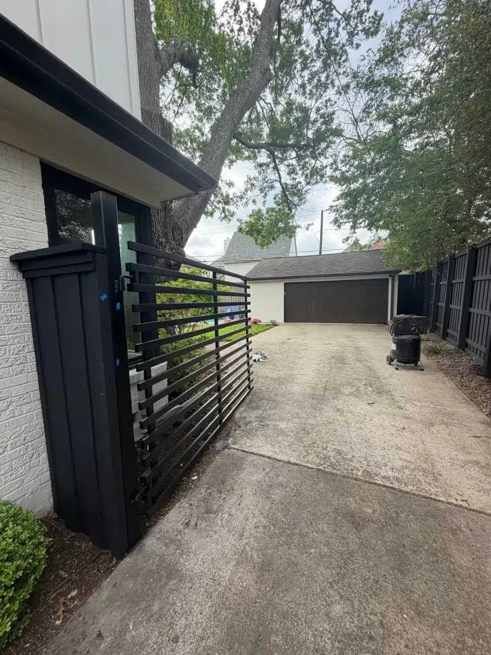 Modern iron gate beside the refinished black-stained fence