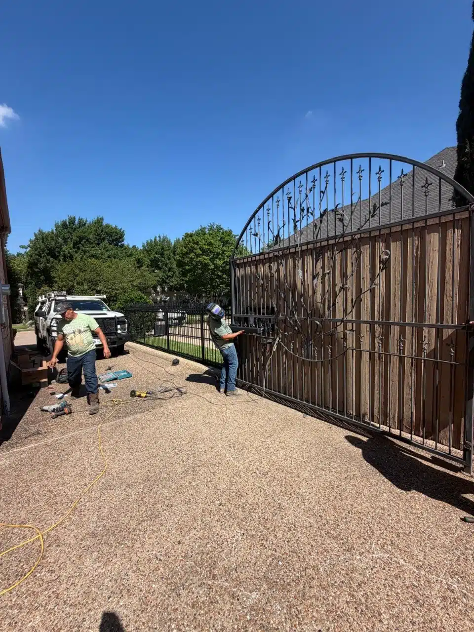 Arched ornamental iron entry gate at a Plano property during repair work
