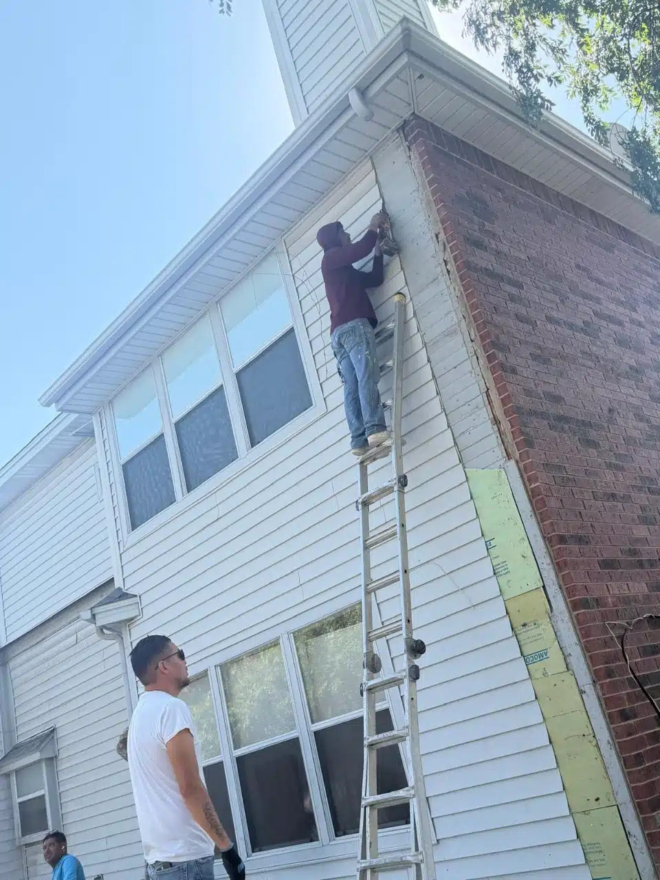 Crew removing siding from the existing wall before the addition is tied in