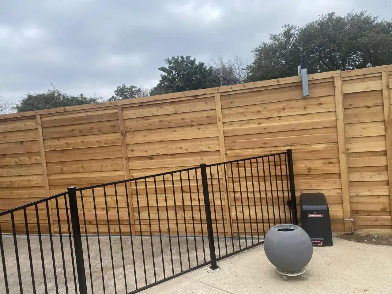 Horizontal slat fence meeting the black iron pool fence