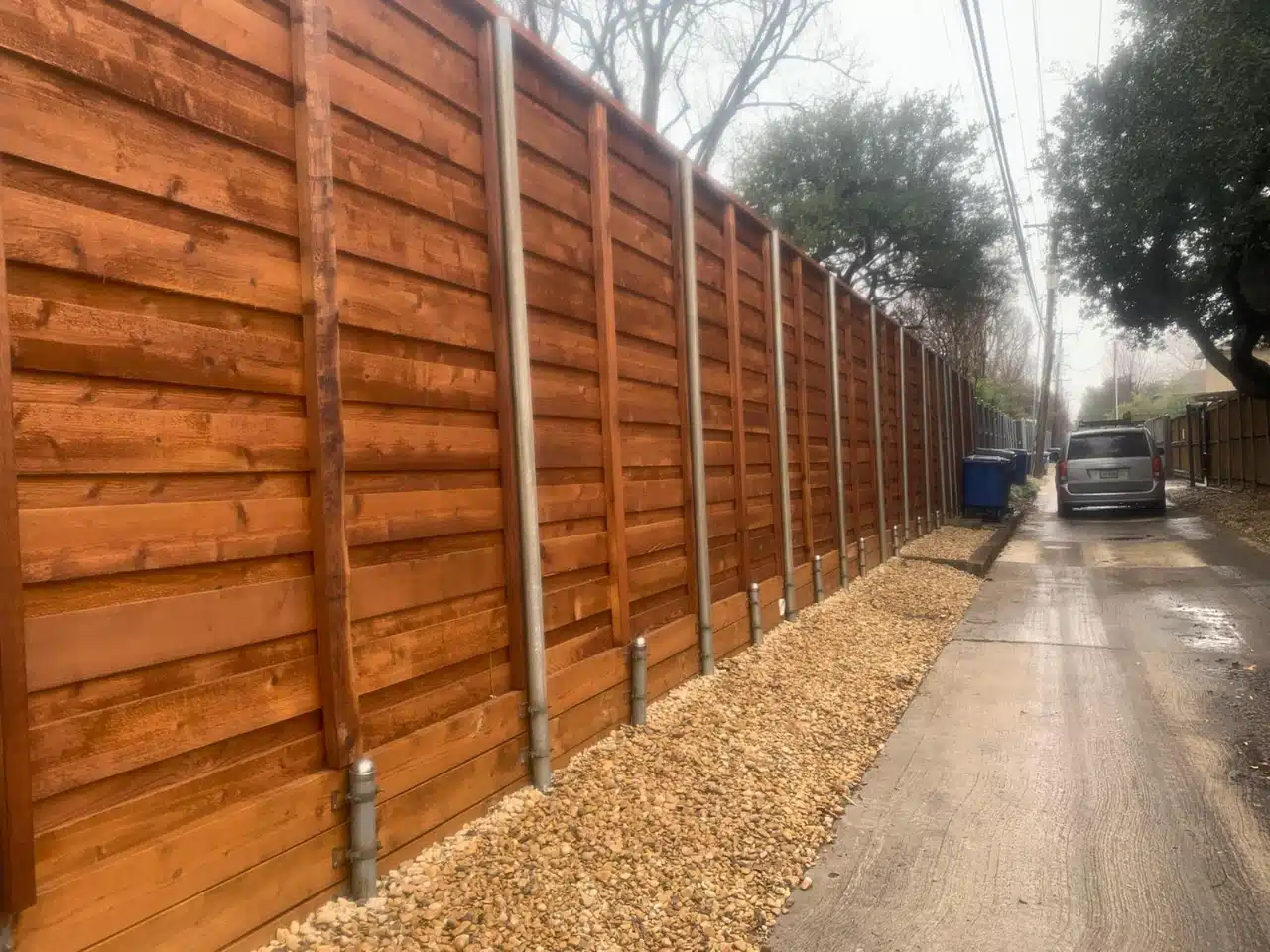 Steel posts carrying the horizontal cedar fence along the alley