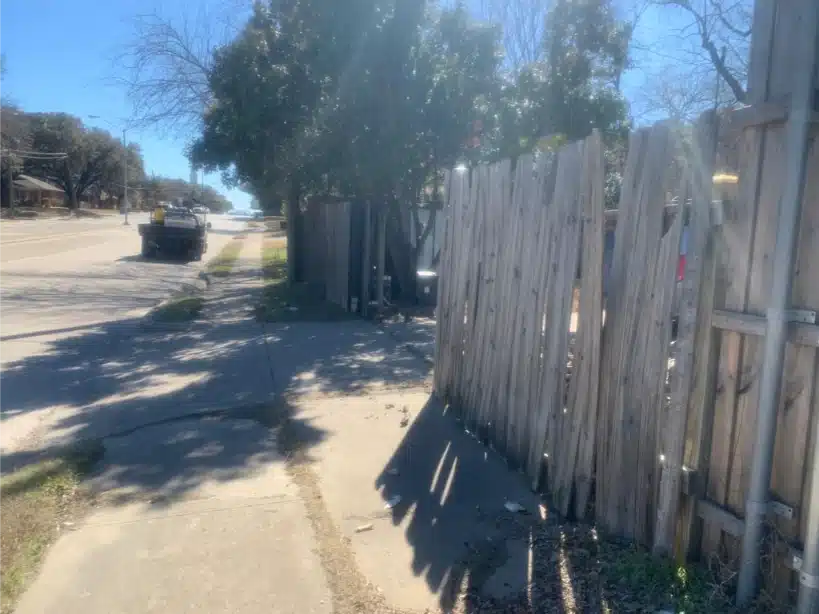 Old grey cedar fence leaning and failing before replacement