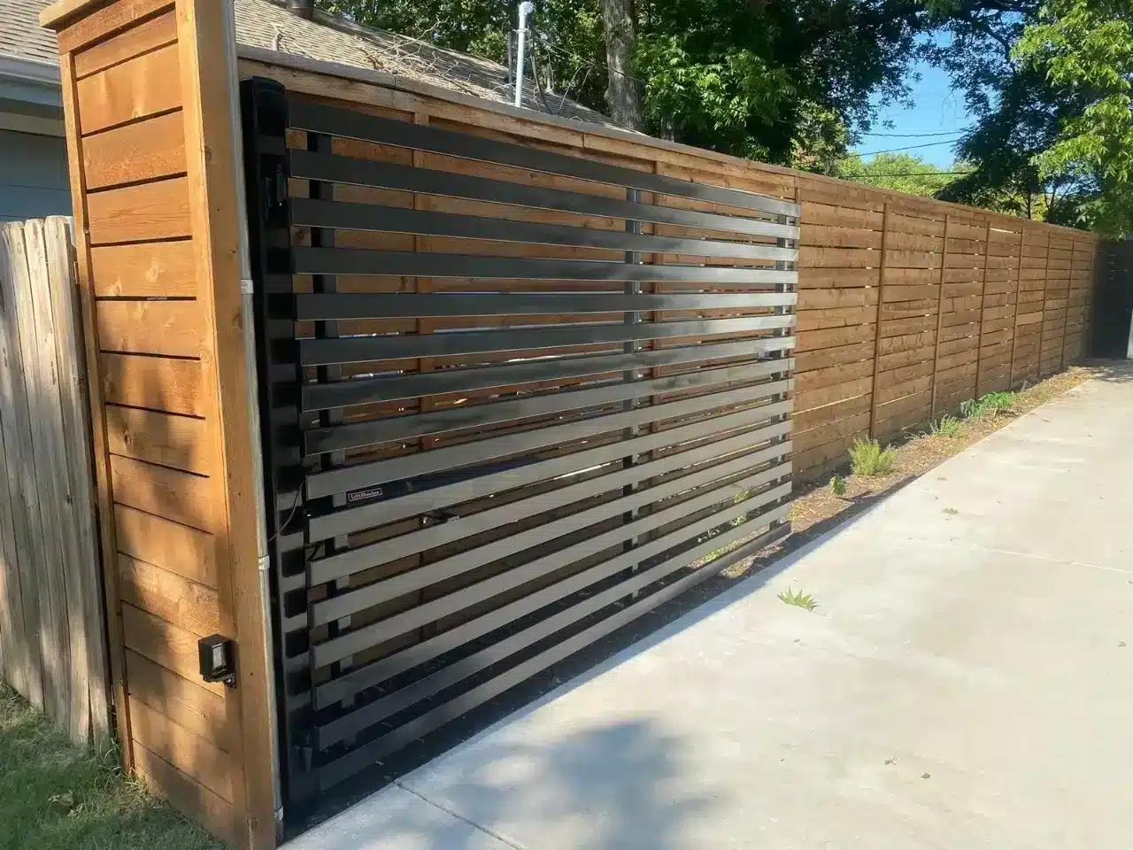 Modern driveway gate with alternating brown wood and dark metal horizontal slats