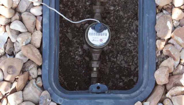 Residential water meter inside an underground utility box with exposed piping, indicating a possible faulty water meter.