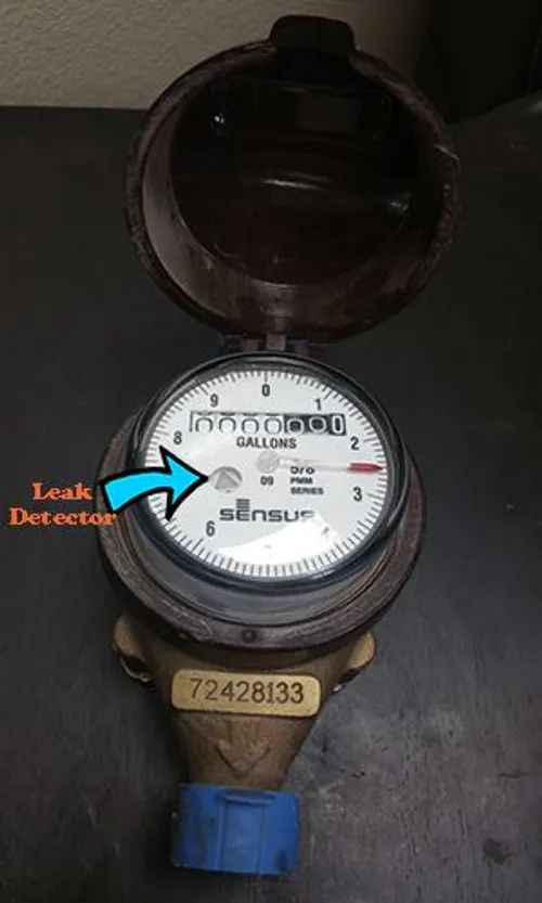 Close-up of a faulty water meter showing the leak detector indicator moving despite no active water use.