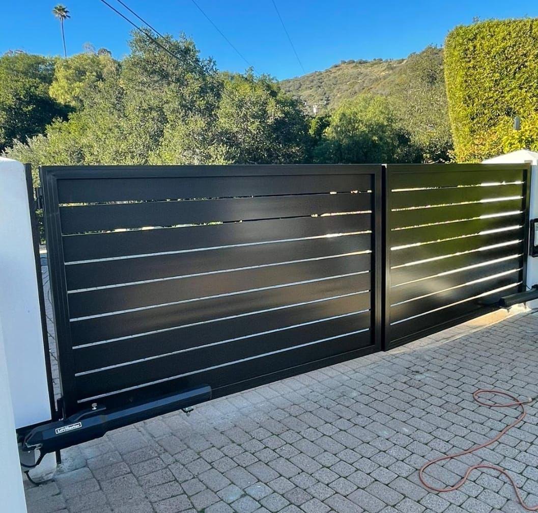 Modern black automated gate with horizontal slats at a residential driveway entrance.